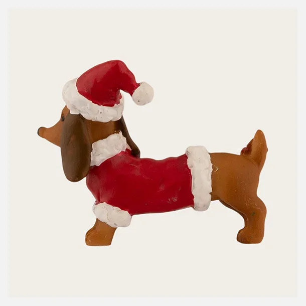Gravhund med nissehue som dekorativ julefigur, 6 cm bred.