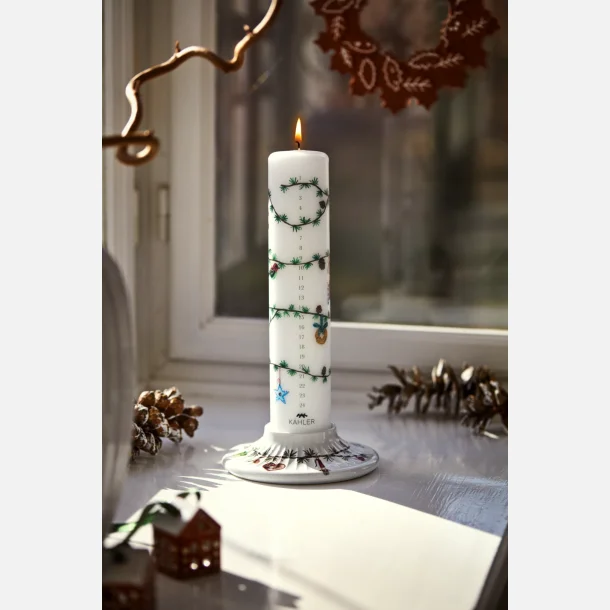 T�ndt K�hler kalenderlys i juledekoreret lysestage p� en hyggelig vindueskarm.